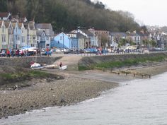 a group of people standing on the side of a river next to houses and boats