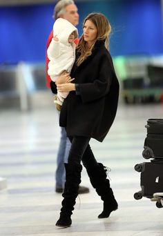 a woman holding a baby in her arms while walking through an airport