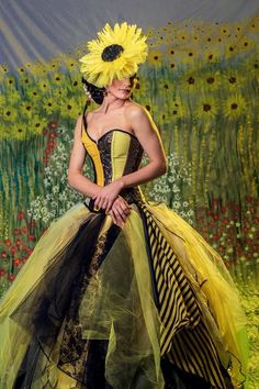 a woman in a yellow and black dress with a sunflower on her head