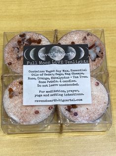 four moon cakes in a clear box on top of a wooden table with information about them