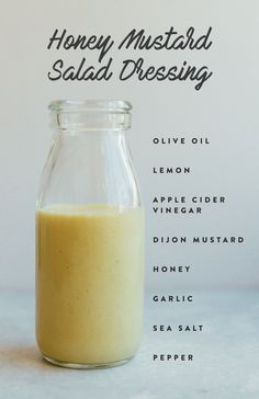 a glass jar filled with liquid sitting on top of a white counter next to the words honey mustard salad dressing