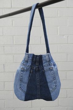 a denim purse hanging from a metal bar