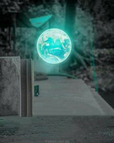 an image of the earth as seen through a green light in front of some trees