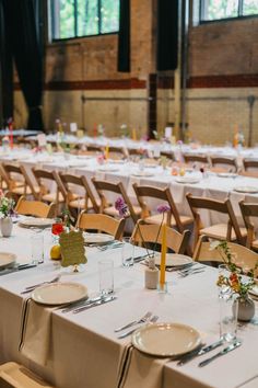 the tables are set up for an event with white linens and yellow napkins