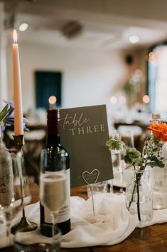 the table is set with wine glasses, candles and cards for guests to write their names