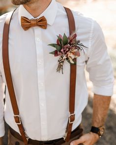 a man wearing a bow tie and suspenders with a flower in his lapel