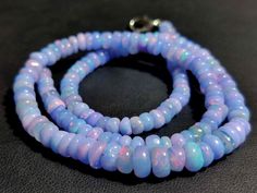 two strands of blue and pink glass beads on a black surface with a silver clasp