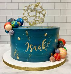 there is a blue cake with gold stars and planets on the top that says saak