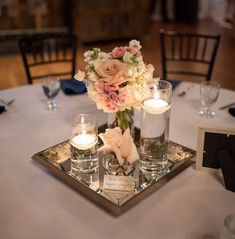 the centerpieces on this table are filled with flowers and candles