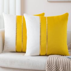 two yellow and white pillows sitting on top of a couch