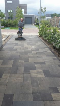 a man is using a floor scruber to clean the walkway in front of his house