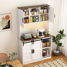 a kitchen with white cupboards and shelves filled with food on top of wooden floors next to a potted plant