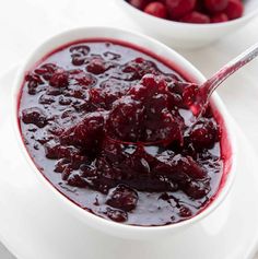 a bowl filled with cranberry sauce next to another bowl full of raspberries