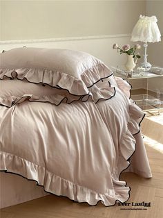 a bed with ruffled sheets and pillows in a room