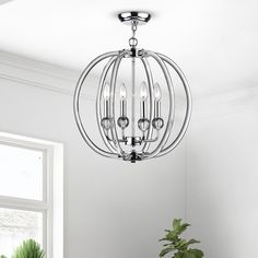 a chandelier hanging from the ceiling in a white room with potted plants