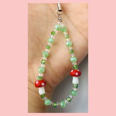 a hand holding a green and red beaded necklace