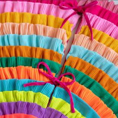 there are many different colors of pleated material on the table together, including pink, orange, yellow, green, and blue