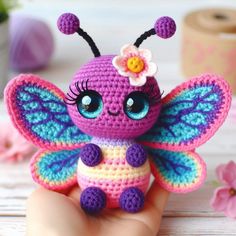 a small crocheted toy with a flower on it's head and wings