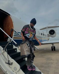 a man standing on the steps of an airplane with his handbag in front of him