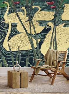 two white swans swimming in the water near tall grass and reeds, against a wall mural