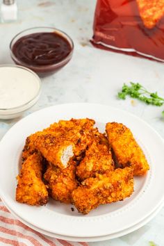 some fried food on a white plate with dipping sauces in the backgroud