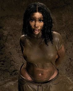 a woman is covered in mud and posing for the camera with her hands on her hips