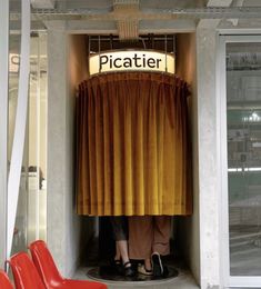 two people standing in front of a curtain with the word picatir on it