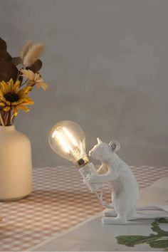 a white bear lamp sitting on top of a table next to a vase filled with flowers