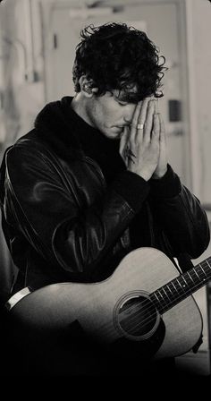 black and white photograph of a man holding his hand to his face while playing the guitar