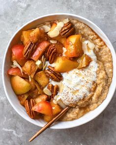 a bowl filled with oatmeal topped with pecans and sliced peaches