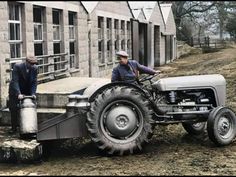 two men standing next to an old tractor