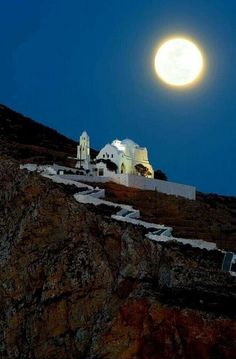 the full moon is setting over some white buildings