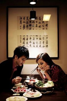 a man and woman sitting at a table eating food