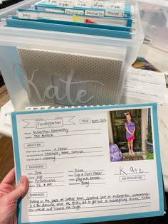 a person holding up a fake photo in front of some folders