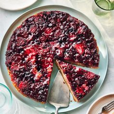 a blueberry cheesecake on a plate with a slice cut out and ready to be eaten