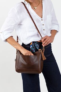 Your bag is proudly made in Lynchburg, Virginia using the finest materials in the world. 10.5" top length 8.5" base length x 3"W x 8"H E xterior back phone pocket 7.5"L x 4.75"H Crafted with vegetable tanned Mocha Tuscan* Italian leather Removable/adjustable 1/2" crossbody strap that extends from 36" to 48" bench made with brown English Bridle leather* and solid brass hardware Interior key clip Pinstripe fabric lining Removable horse hair tassel Solid brass hardware Made in the USA *Mocha Tuscan Pinstripe Fabric, Horse Hair Tassels, Lynchburg Virginia, English Bridle, Leather Sling Bag, Key Clip, Dark Denim Jeans, On The Farm, Leather Cleaning