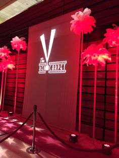 the red carpet is lined up with tall pink flowers and lighted poles in front of it