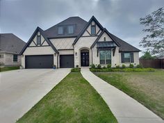 a large house with two car garages in the front yard and grass on the side