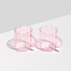 two pink glass mugs sitting next to each other