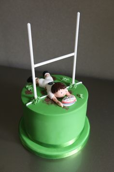 there is a cake with a soccer goal and ball on it that has been made to look like a kid laying in the grass