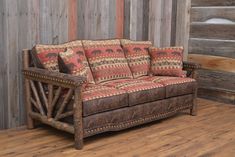 an old couch sitting on top of a hard wood floor next to a wooden wall