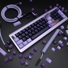 a computer keyboard with purple and black keys on it, surrounded by other electronic gadgets