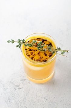 a glass filled with orange juice and garnished with green sprigs on top