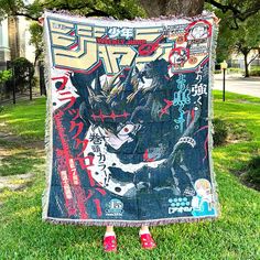 a person standing in the grass holding up a blanket with an image of godzilla on it