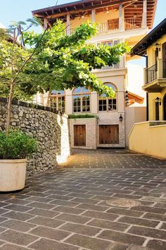 an outdoor courtyard with potted plants on the side and a stone wall around it