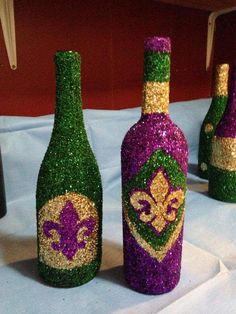 three wine bottles are decorated with purple and green glitters