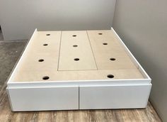 a white bed frame with holes in the middle and two drawers on each side for storage