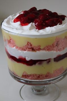 a layered cake with white frosting and cherries on top is displayed in a glass dish