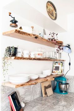 a kitchen counter topped with lots of bowls and pans on top of wooden shelves