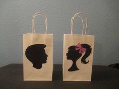 two paper bags with silhouettes of women's heads on them, one has a pink bow